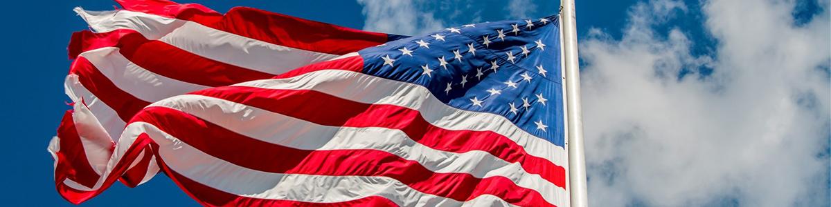 United States Flag waving in front of a clear, blue sky